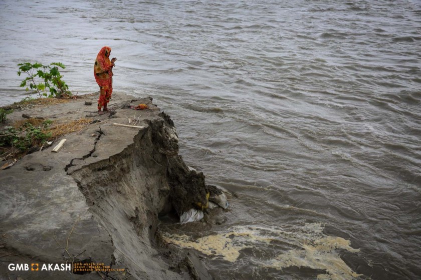 A woman stands beside the River Jamuna where erosion is eating into its banks.